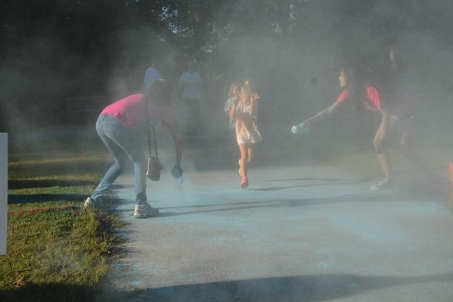 Volunteers throwing blue color powder on runners during the Color the Creek race at CreekFest Houston