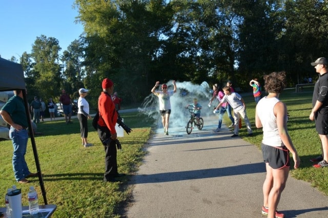 Runner crossing the finish line with arms raised during the Color the Creek race at CreekFest Houston