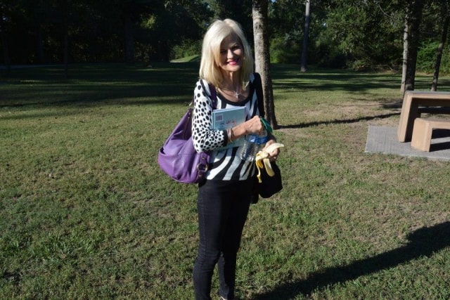 Woman with a purple bag and CreekFest program standing on the grounds at CreekFest Houston