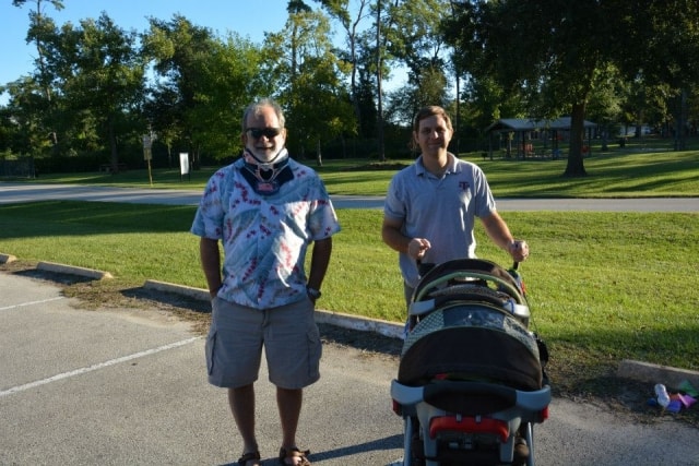 Two men standing together near a baby stroller on the Cypress Creek greenway at CreekFest Houston