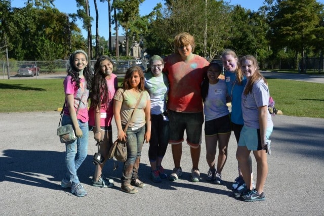 Group of eight young people covered in color powder posing together after the Color the Creek race at CreekFest