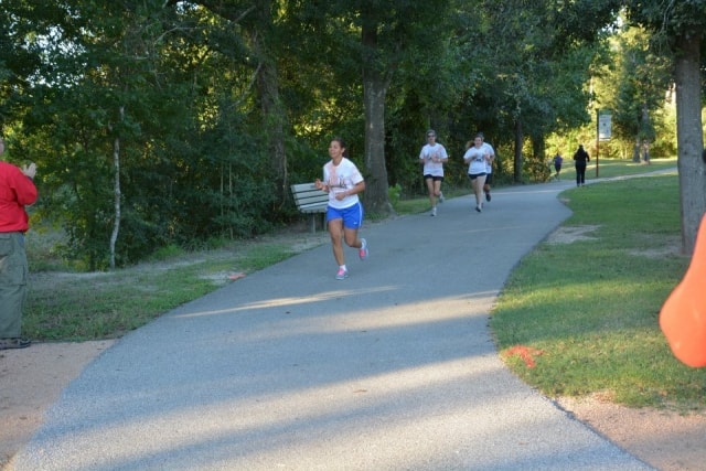 Three runners on the Cypress Creek greenway trail during the Color the Creek race at CreekFest