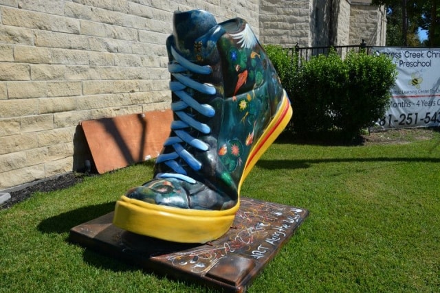 Large decorative painted sneaker sculpture on the lawn outside Cypress Creek Christian Community Center at CreekFest