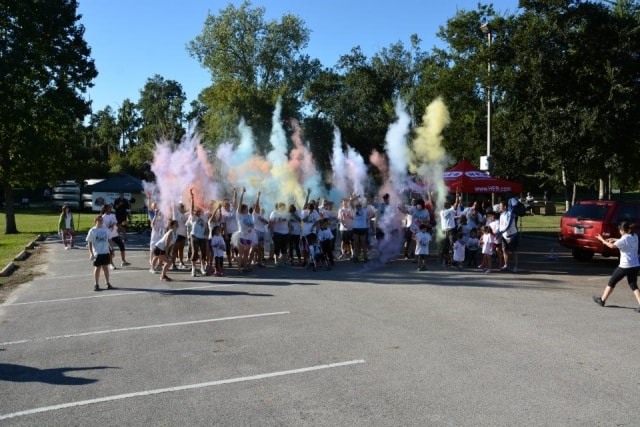 Large crowd of participants throwing multicolored powder into the air at the Color the Creek race finish at CreekFest Houston