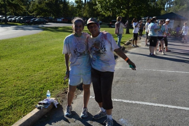 Two women covered in color powder smiling together after the Color the Creek race at CreekFest Houston