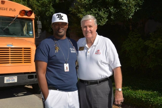 Two attendees posing in front of a school bus at CreekFest