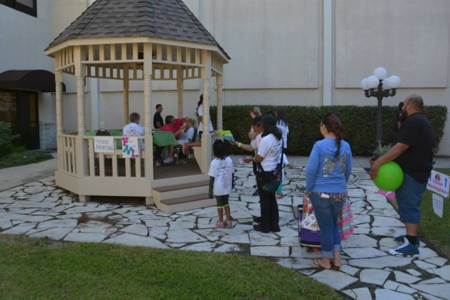 Families gathered around the gazebo face painting booth at CreekFest