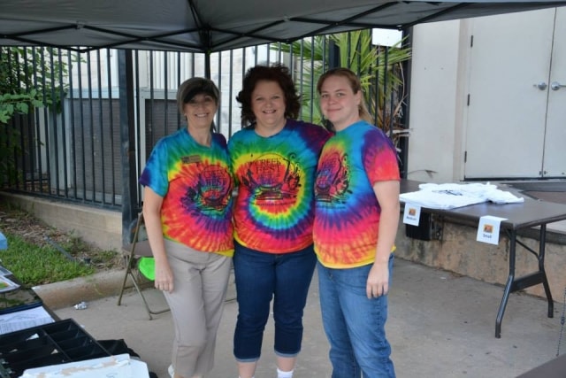 Three volunteers in tie-dye CreekFest t-shirts at the festival