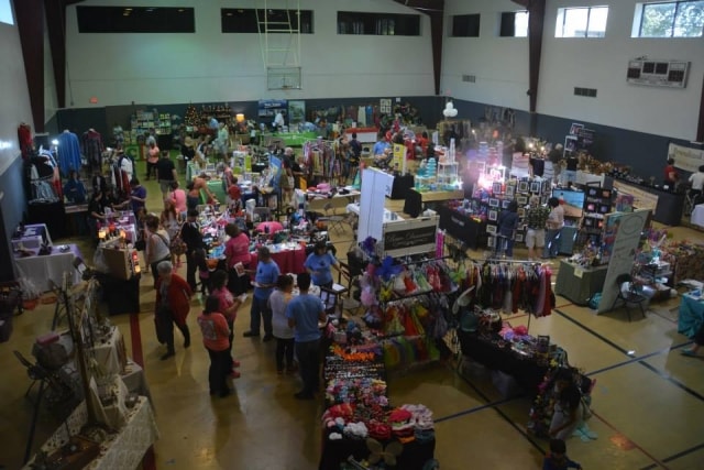 Indoor marketplace with vendor booths and shoppers at CreekFest Houston
