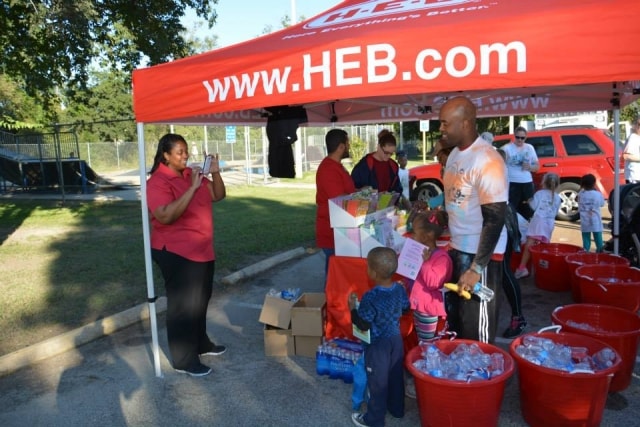 Families gathering under the H-E-B tent with food and supplies at CreekFest