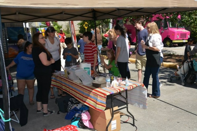 Attendees browsing a vendor booth under a canopy at CreekFest Houston