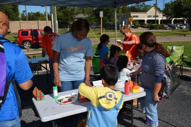 Home Depot volunteers helping children with craft projects at CreekFest