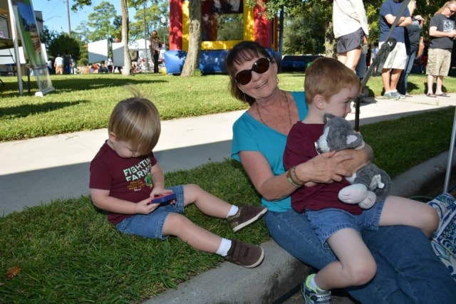 Grandmother sitting on the grass with two young grandchildren at CreekFest Houston