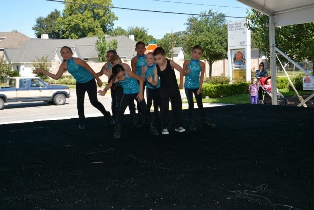 Children in teal sequin costumes performing a dance routine on the CreekFest main stage