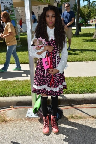 Young girl in a floral dress holding a small dog at the CreekFest dog show
