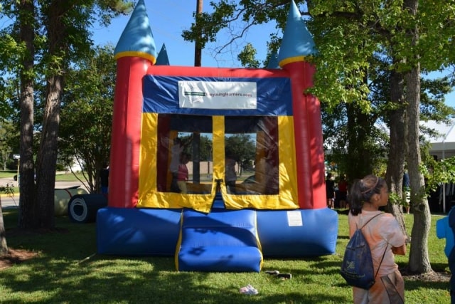 Colorful inflatable bounce castle with a child looking on at CreekFest Houston