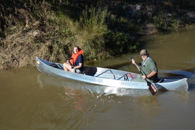 Father and daughter paddling an aluminum canoe on Cypress Creek at CreekFest