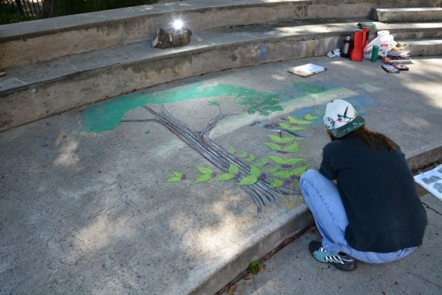 Chalk artist creating a detailed tree mural on outdoor steps at CreekFest Houston
