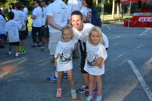 Father posing with two young daughters in CreekFest t-shirts before the Color the Creek race
