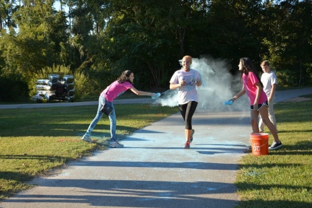 Volunteers throwing blue color powder on a runner during the Color the Creek race at CreekFest