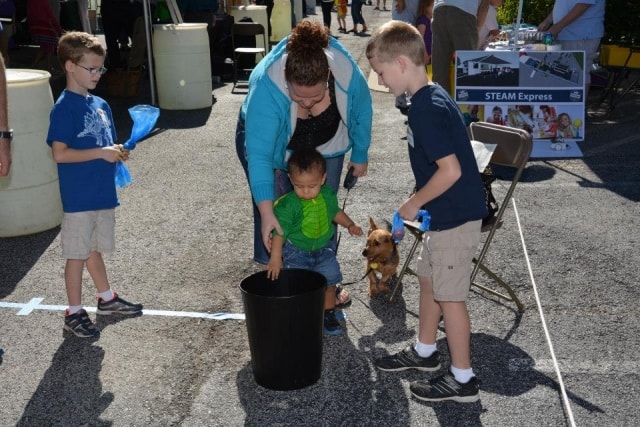 Children and adult at the STEAM Express activity booth with a small dog at CreekFest Houston