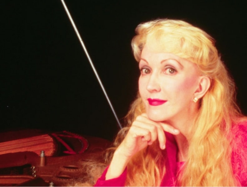 Performer seated at piano in pink dress
