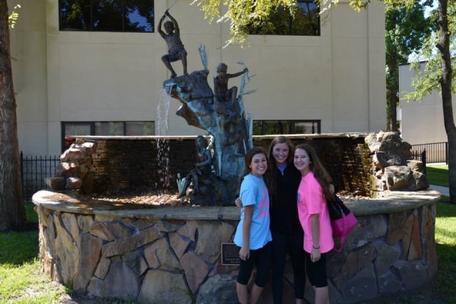 Three young women posing in front of the Hendrix fountain sculpture