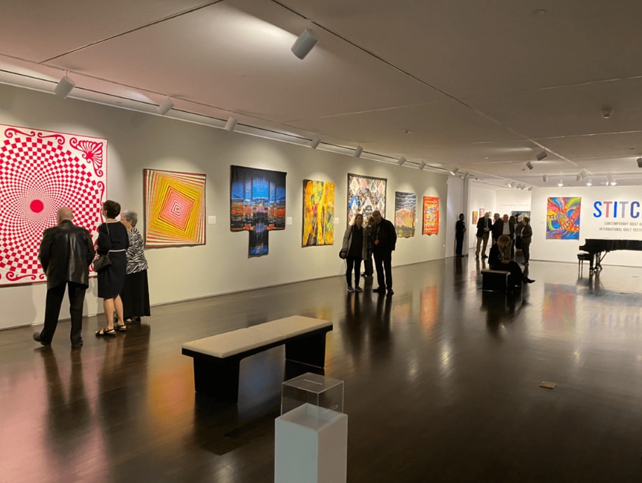Visitors viewing quilts and artwork at Pearl Fincher Museum STITCH exhibition