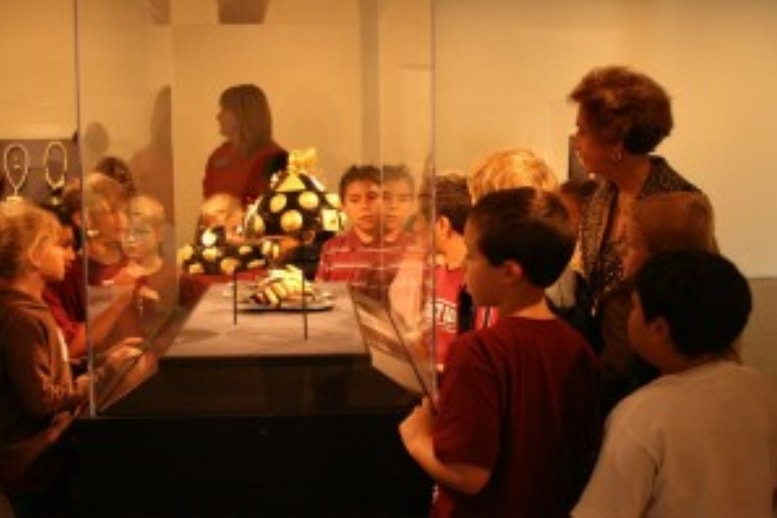 Children with docent gathered around a display case at Pearl Fincher Museum